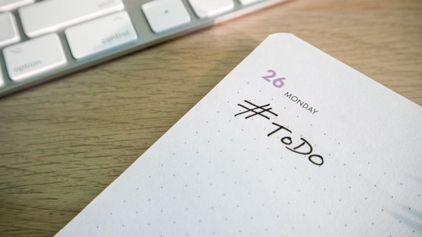Close-up of a to-do list next to a computer keyboard on a desk.